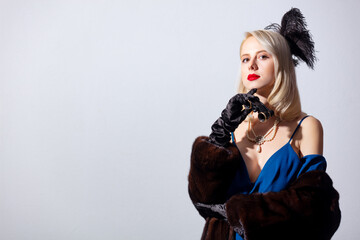 Blonde woman in vintage blue dress and fur coat with opera glasses