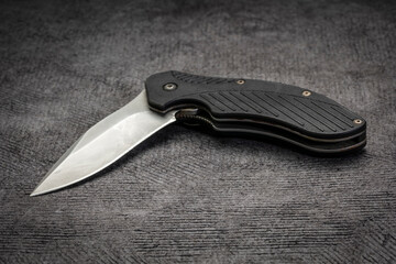 partially  opened, used pocket knife with assisted opening on a black textured paper