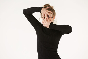 A girl in black clothes on a white background depicts the emotion