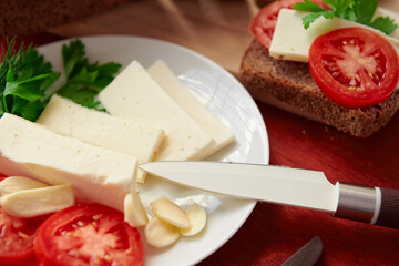 healthy food - fresh bread and feta cheese on a wooden background, tomatoes, greens and vegetables