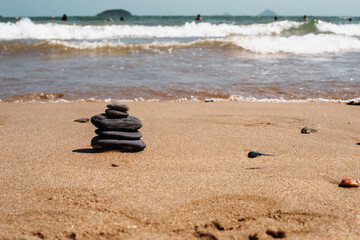 Fototapeta na wymiar Black flat zen stones lie on the sand of a sea beach