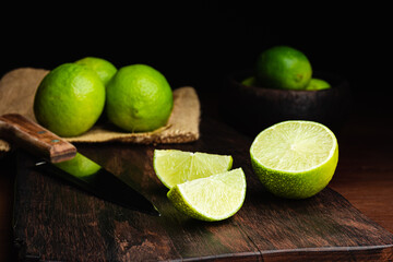 Fresh, raw and organic sliced green lemon in focus with other lemons in composition