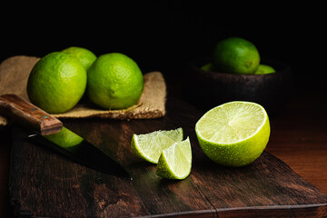 Fresh, raw and organic sliced green lemon in focus with other lemons in composition