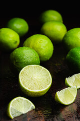 Fresh, raw and organic sliced green lemon in focus with other lemons in composition