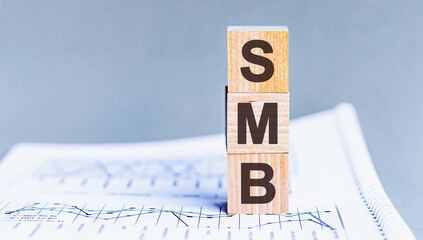 Pile with three wooden cubes - letters SMB meaning Small to medium sized business on them, space for text.
