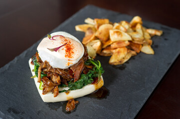 grilled sweet and salty think sliced steak, sautéed spinach with poached egg on steamed bun bread with home potato fries on stone plate