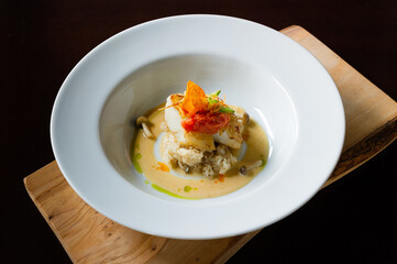 sautéed cod fish with mushroom risotto with broth in a white bowl