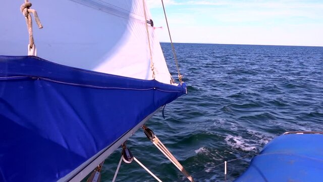 A sailing yacht boat in calm coastal waters with a nice breeze on a sunny day. Looking astern over the mainsail. Relaxing, mesmerising, gliding along with just the help of the wind.