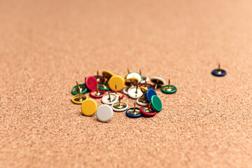 Perspective view of multi colored thumb tack over a cork board