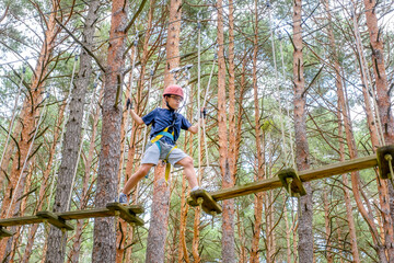 woman crossing a tibetan bridge in an adventure park in a pine forest