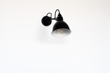 Close up view of single Black and modern wall lamp on white wall