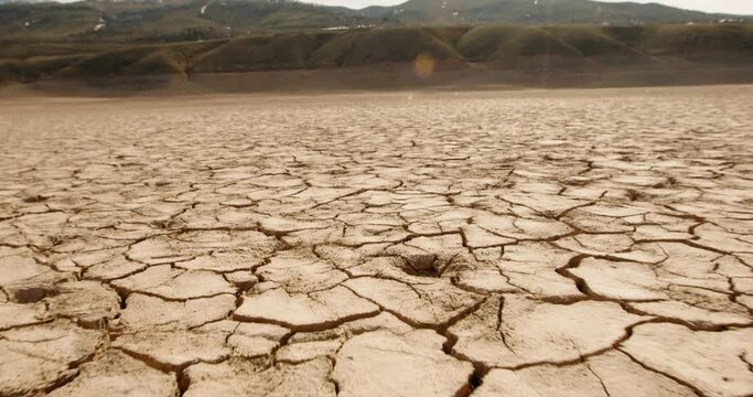 Dynamic shot of cracked soil ground of dried lake or river in mountains. Land destroyed by erosion and global warming - ecological issues concept 4k footage