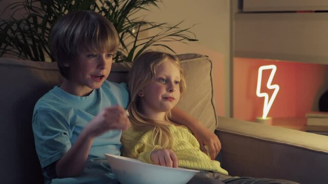 Portrait of children while watching TV. Boy and girl watching cartoon.