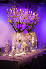 Wedding table with blue ambient lighting and white flower decor with floating candle containers