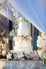 White fondant wedding cake decorated with pink and white roses on a ceremonial table