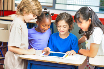 Fototapeta premium Elementary school scene. Multi ethnic classmates in the classroom learning together