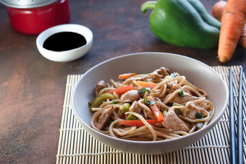 Chinese noodles, yakisoba with vegetables and chicken, homemade food. Chopsticks.
