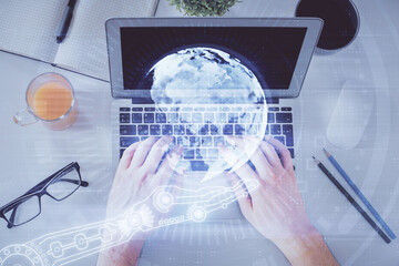 Multi exposure of man's hands typing over computer keyboard and world map hologram drawing. Top view. Technology concept.