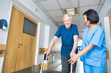 Asian nurse assisting elderly man with walker walking on the hospital floor