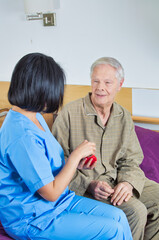 Obraz na płótnie Canvas Asian nurse assisting elderly man on the hospital bed