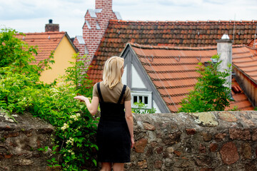 Fototapeta premium blonde girl stay near old city tile houses in Europe