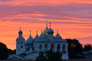 Obraz premium Veliky Novgorod. Russia. Novgorod Kremlin. Sunset. Domes of St. Sophia Cathedral, belfry and chapel against the background of a beautiful sunset sky