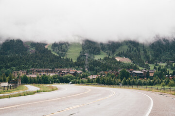 Teton Village, Wyoming -  Low hanging rain clouds loom over the ski village town in the Grand Tetons mountain range. Road leading into town
