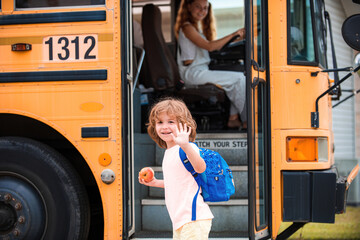 School boy at the front of the school bus with apple and bag.