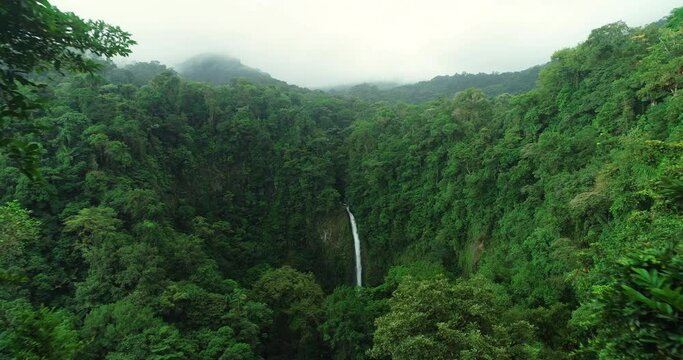 La Fortuna Waterfall in the rainforest near Arenal Volcano in Costa Rica, Central America. Beautiful nature landscape at toursit travel destination landmark. Aerial drone video footage.