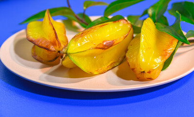 Fototapeta na wymiar carambola fruits served on plate on blue background