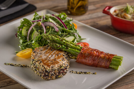 Juicy beef steak with green salad on white plate with aspergus. Top view, placement