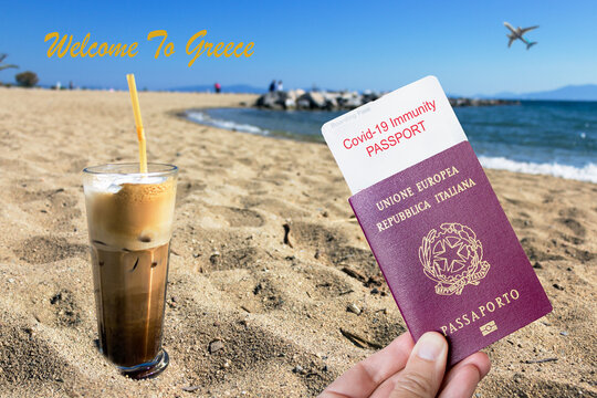 Male hand holding an european passport with a covid-19 immunity certificate over a frape coffee on the beach. Greek tourism opening concept.