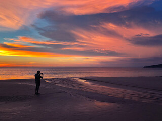 Fototapeta na wymiar Panoramic view of sunset a man taking photo at Karon beach in Phuket, Thailand