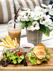 Smoked salmon croissant sandwich served with coffee and french fried