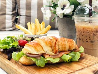Smoked salmon croissant sandwich served with coffee and french fried