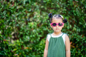 Cute little girl standing at garden in summer.