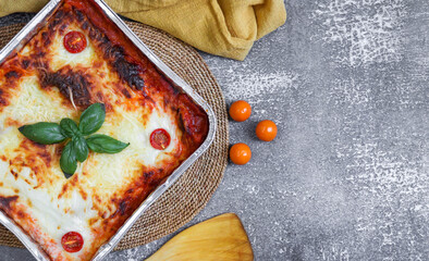 
Ready-made lasagne on a gray concrete background on the left and with space for text on the right,...