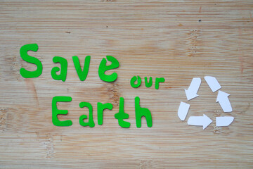 Phrase of Earth day. Saving our earth, go green, recycle symbol concept background on wooden board
