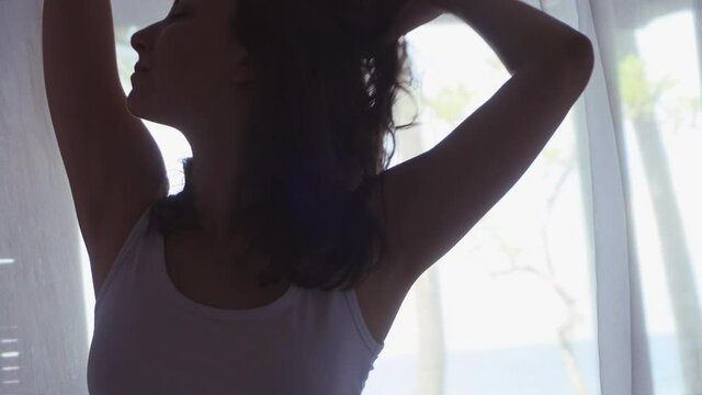 Happy beautiful girl in morning in the bed with white bedsheets and curtains, smiling in bungalow on sea cite on island