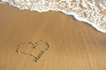 Drawn the Heart on the sand of a sea beach.