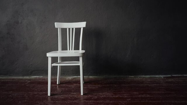The white chair stands in an empty room with brown floors and gray walls