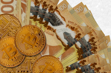 100 Canadian dollars bills and golden bitcoins. Cryptocurrency investment concept. Crypto mining or...
