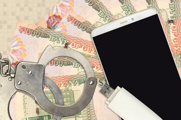 1000 Guyanese dollars bills and smartphone with police handcuffs. Concept of hackers phishing...