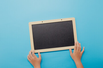 Child hands holding a blank blackboard