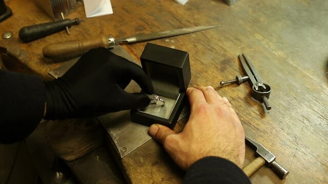 jewelery master hand made diamond solitaire ring putting engagement in box on the craftsman workshop table. jewelery master
