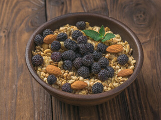 Fresh black raspberries, almonds and granola in a clay bowl.