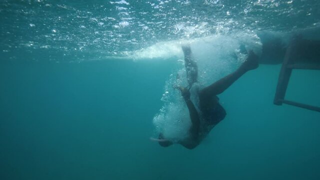 A man in snorkeling mask filming selfie video while falling off from a boat