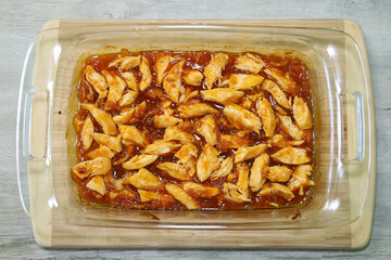 Apricot chicken in baking dish. Dinner leftover casserole, shredded for storing.