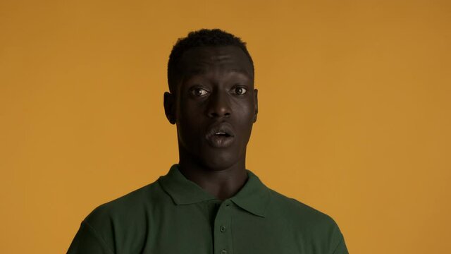 Young shocked African American man scaredly turning away and gesturing stop over colorful background. Don't want to watch expression