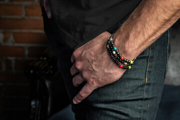 Elegant bracelets made of natural stones and minerals on a courageous hand. Close-up, on a brick wall background.